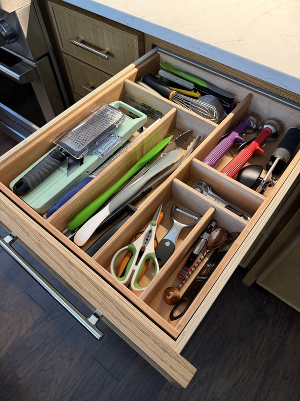 Open kitchen drawer in maple with various utensils and tools neatly arranged.